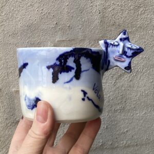 stjernekop med tekst Voldsmonopol. unika håndlavet keramik kop med ansigt. Håndlavet og modeleret i porcelænsler. glaseret i blå nyancer . unikkop. Ansigtskop.