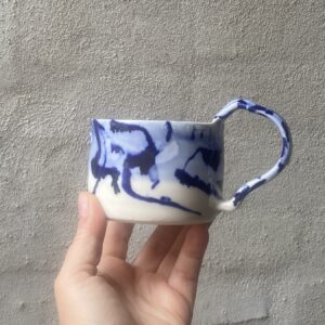 unik i glasur og skæv og oval i formen. Håndlavet og drejet keramik. Porcelæn. Lille personlighed. unik kop med ansigt. med særlig glasering cobolt blå..